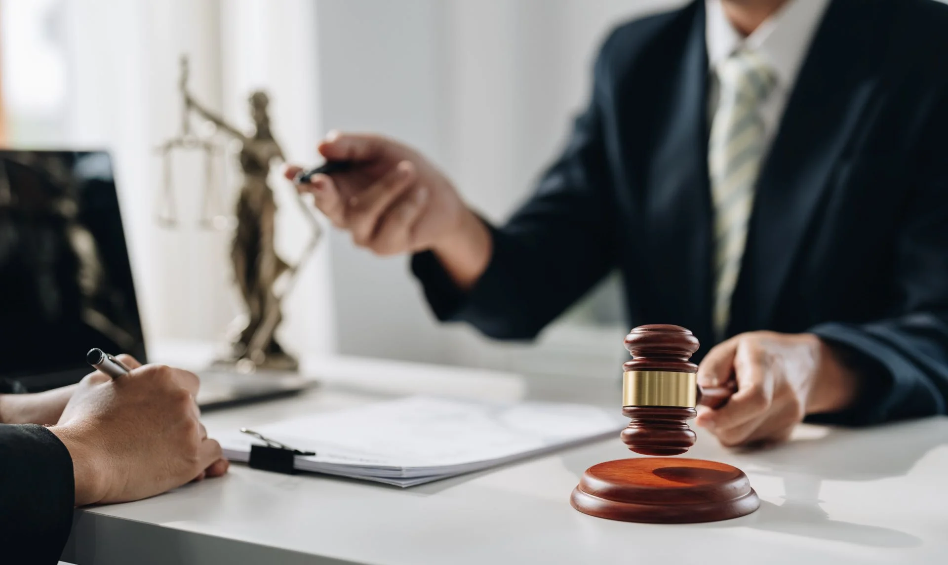 A lawyer in an office with a client speaking with a client and holding a gavel.