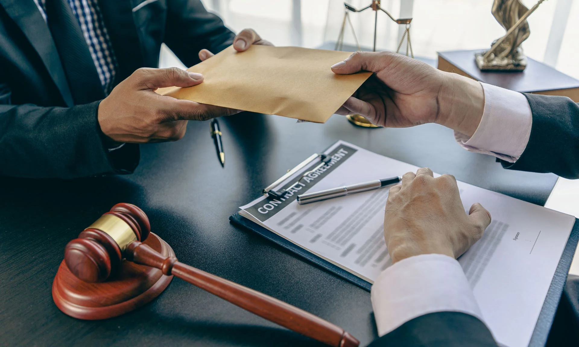 A lawyer meeting with his client and handing him an envelope containing payout from insurance.