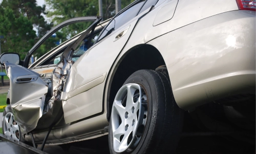 A grey car with a caved-in door caused by an accident.