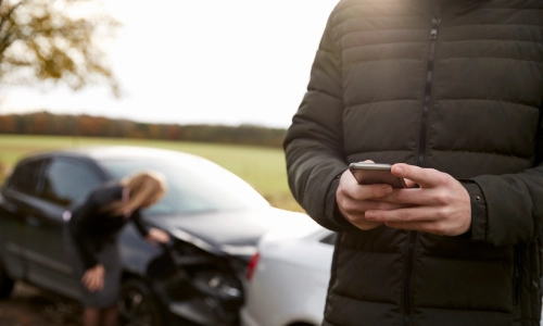 A depth of field shot of a driver calling for assistance after his car got caught in an accident.